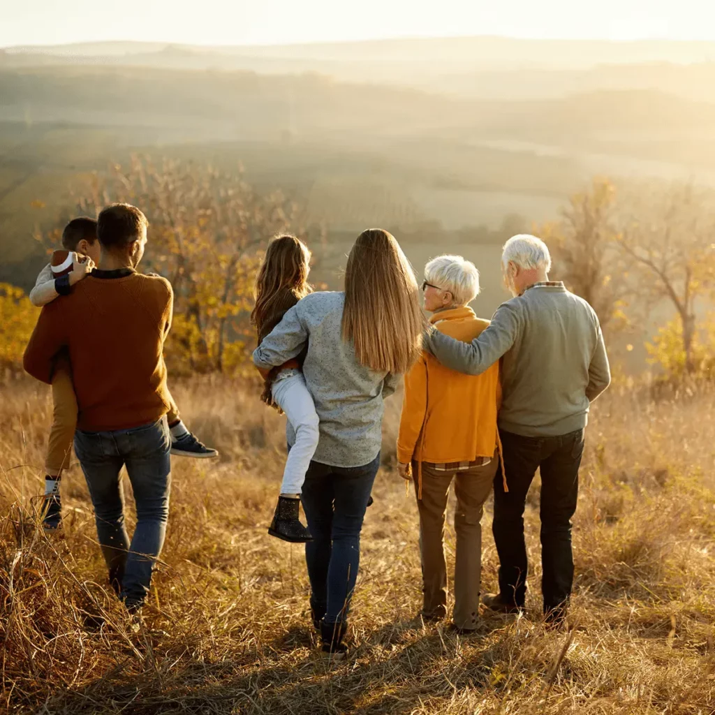 Famille multigénérationnelle se promenant dans la campagne au coucher du soleil.