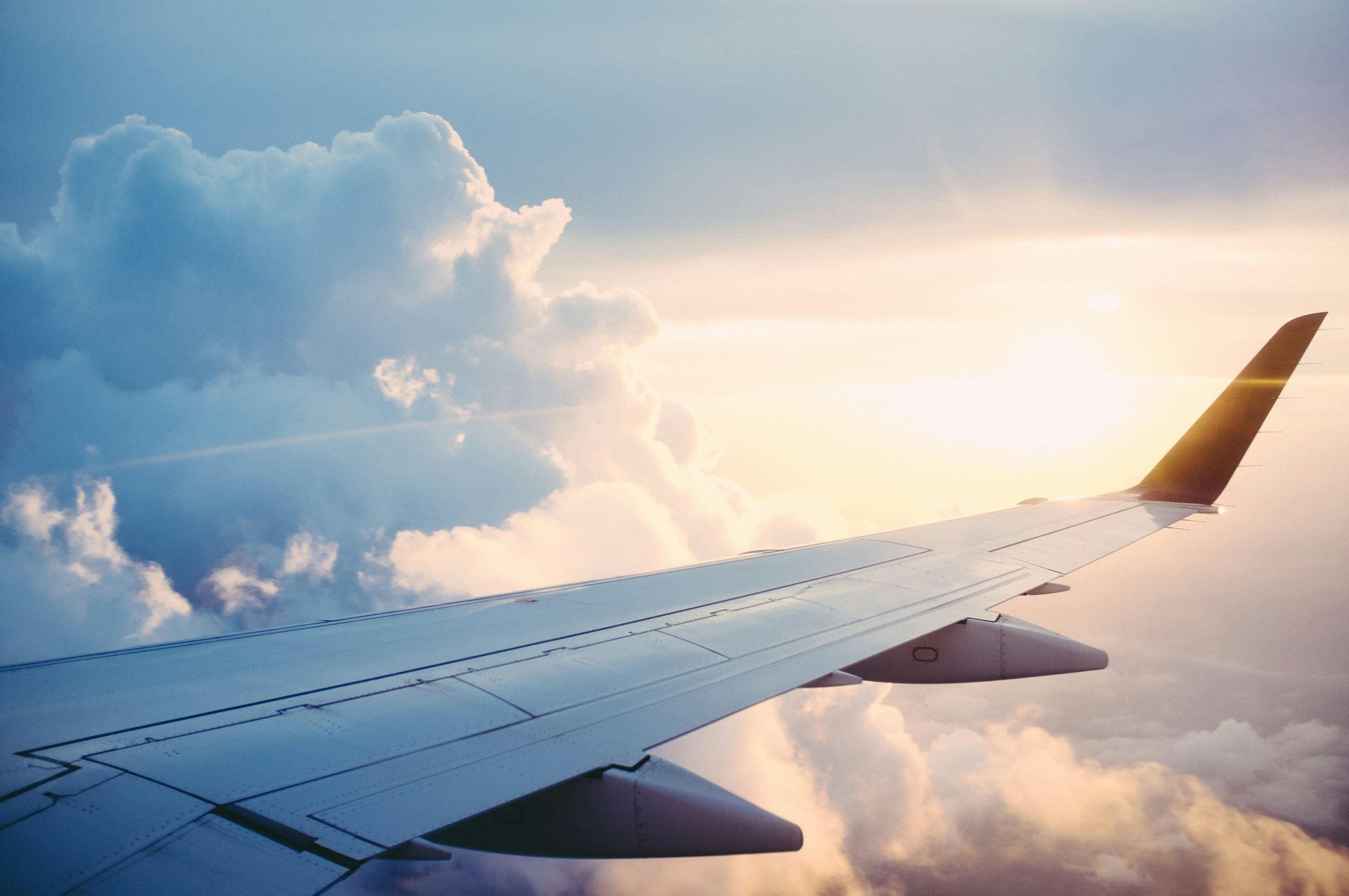 Aile d'avion au-dessus des nuages illustrant le transfert du défunt lors d'un rapatriement de corps