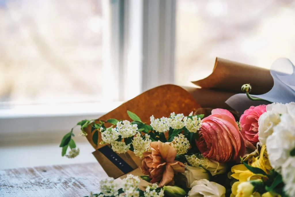 Bouquet de fleurs fraîches et colorées posé près d'une fenêtre.