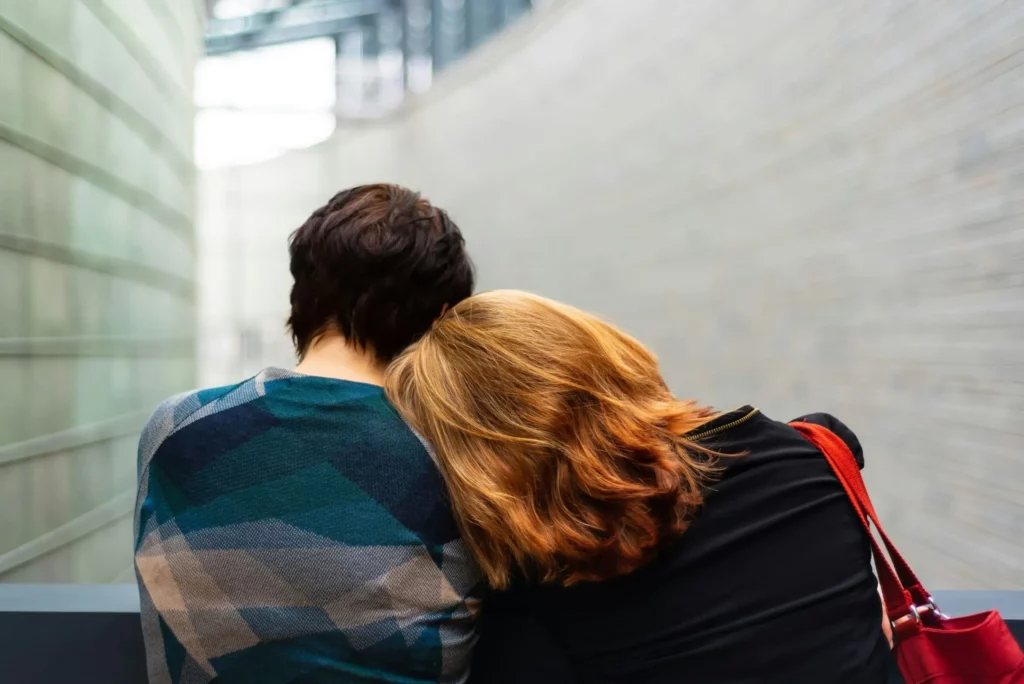 Deux personnes se soutenant, l'une posant sa tête sur l'épaule de l'autre.